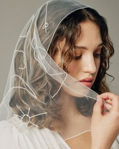 a woman wearing a veil and holding her hair