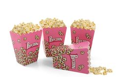 three pink boxes filled with popcorn sitting next to each other