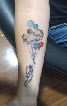 a person with a tattoo on their arm holding balloons