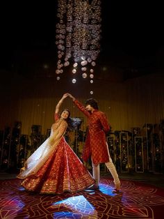 two people are dancing on a stage with lights in the sky behind them and chandeliers hanging from the ceiling