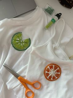 a pair of scissors sitting on top of a white t - shirt next to some sequins