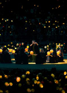 a group of people standing on top of a stage surrounded by balloons in the air