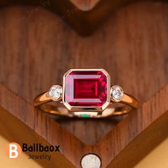 a close up of a ring with a red stone in it on a wooden surface