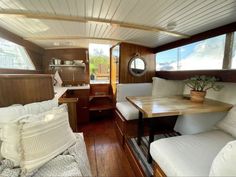 the interior of a boat with wood flooring and white pillows on top of it