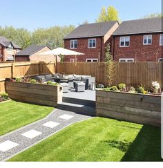 an outdoor patio area with grass and wooden fenced in areas for seating, plants and flowers