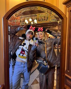 two people dressed up as mickey and minnie mouse posing for a photo in front of a mirror