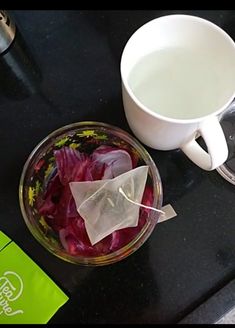 a bowl of red cabbage and a cup of water on a counter top next to a blender