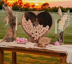 a table with flowers and candles on it in the middle of a grassy field at sunset