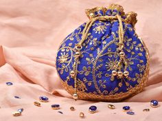 Blue Potli Bag with Pearl Handle Strap With its classy zari work and a pearl handle strap all in gold this Blue Potli Bag is ideal for this wedding season. Fabric Raw Silk Color Royal Blue Embroidery Zari Work in Gold Size amp Dimensions Height - 8 inWidth - 7.5 inDepth - 1.5 in Strap Pearl Handle Strap Closure Tasseled Drawstring Compartments Single compartment Care Wipe with a soft clean amp dry cloth to remove dust When not in use store it in a dust bag for longer product life Avoid liquid ex Traditional Blue Bags For Festivals, Traditional Blue Pouch Bag, Traditional Blue Bags Suitable For Gifts, Blue Embroidered Bag For Festivals, Handwork Pouch As Diwali Gift, Bollywood Style Handwork Pouch As Gift, Festive Handwork Pouch, Festive Handwork Pouch As Gift, Diwali Gift Pouch With Handwork