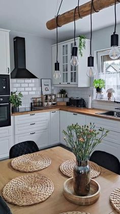 a kitchen with white cabinets and wooden table surrounded by placemats on the floor