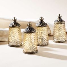 three glass jars sitting on top of a table next to a white towel and pillow