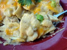 a red plate topped with chicken and cheese covered in sauce, garnished with cilantro