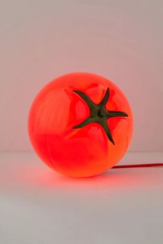 an orange ball shaped like a starfish sitting on top of a white table next to a red cord