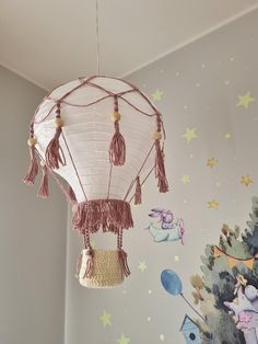 a white paper lantern with tassels hanging from it's ceiling in a child's room