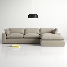 a large sectional couch sitting on top of a white floor next to a black lamp