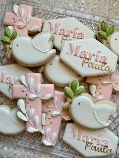 decorated cookies in the shape of doves and flowers on a glass tray with name tags