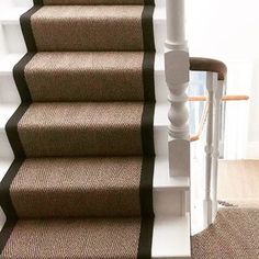 a cat is sitting on the carpeted stairs next to a banister and handrail