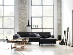 a modern living room with brick walls and floor to ceiling windows that overlook the city