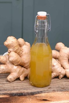 a glass bottle filled with liquid next to ginger roots