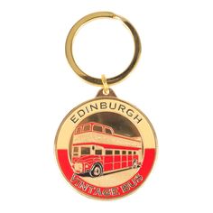 a red and gold coin shaped keychain with an image of a double decker bus