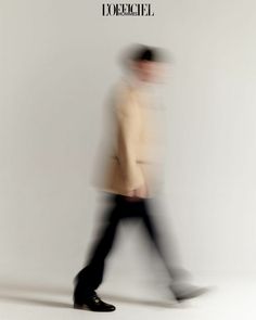 a blurry image of a man in a hat and coat walking across a white background