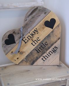 a wooden heart shaped sign that says enjoy the little things with two hearts on it