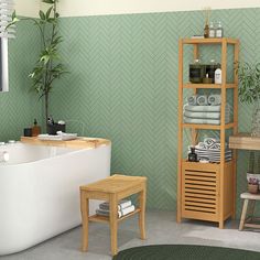 a bathroom with green walls and white bathtub next to a wooden shelf filled with towels