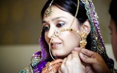 a bride getting ready to put on her jewelry in preparation for the wedding day ceremony