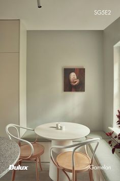 a white table and chairs in a room with a painting on the wall behind it