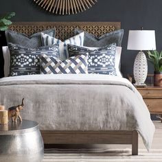 a bed with blue and white pillows on top of it next to a wooden headboard