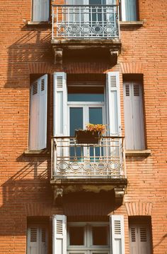 an apartment building with balconies and shutters on the second story, balcony