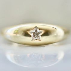 a gold ring with a star on the middle and a small diamond in the center