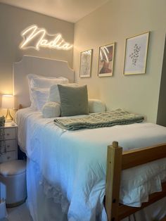 a white bed sitting in a bedroom next to two pictures on the wall above it