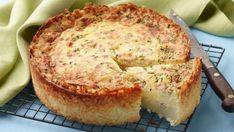 a quiche on a cooling rack with a slice cut out and ready to be eaten