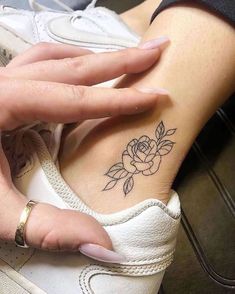 a woman's hand with a rose tattoo on her left wrist and right arm