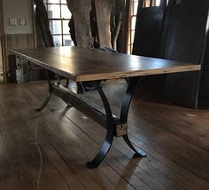 a wooden table sitting on top of a hard wood floor next to a tree in an old building