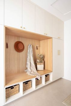 a room with some white cabinets and baskets on the wall next to it is a coat rack