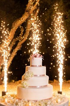 a white wedding cake sitting on top of a table covered in flowers and lit candles