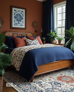 a bedroom with orange walls, blue bedding and potted plants on the floor