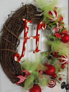 a christmas wreath with the letter h on it and ornaments hanging from the front door