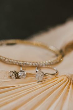 two wedding rings sitting on top of an open book next to a ring with diamonds