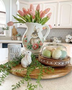 a vase with flowers and eggs on a tray in the middle of a kitchen counter