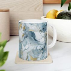 a marbled coffee mug sitting on top of a counter next to some lemons