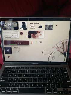 an open laptop computer sitting on top of a red bed cover covered in pictures and text