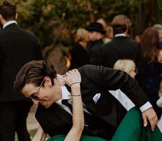 a man and woman in formal attire sitting on the ground with their arms around each other