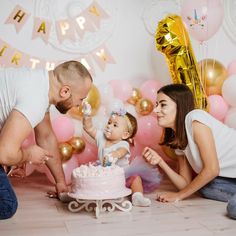 a man, woman and baby are sitting in front of a cake with candles on it