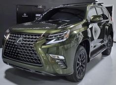 a green suv parked in a garage next to a black wall and white flooring