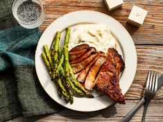 a white plate topped with meat and asparagus