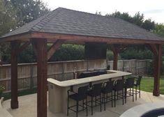 an outdoor kitchen with bar and grill in the back yard