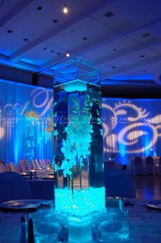 a tall glass vase filled with water and flowers on top of a blue table cloth